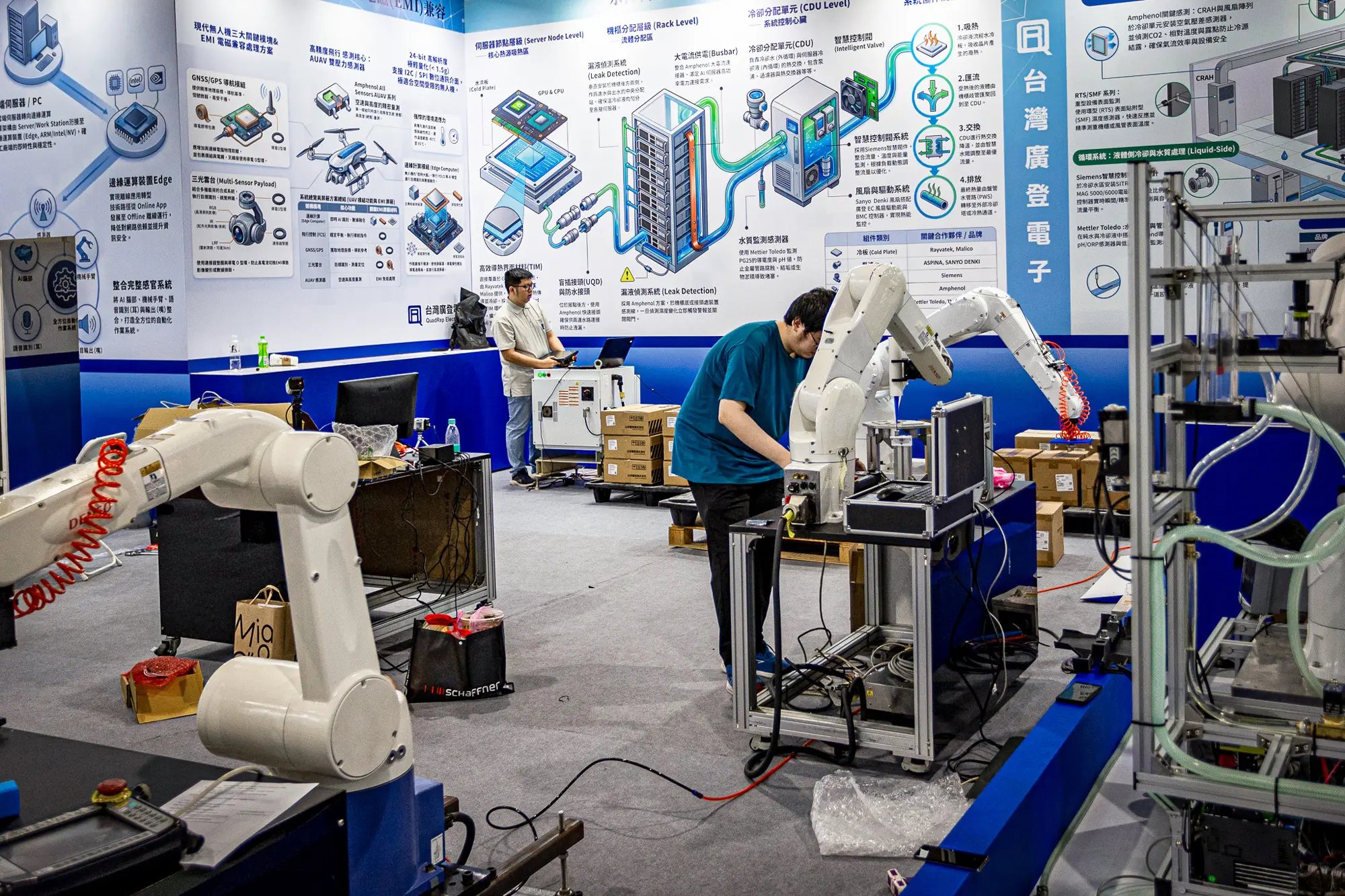 2026年6月1日，在台湾台北举行的COMPUTEX国际电脑展前夕，工程师们正在展位上配置和测试工业机器人手臂。COMPUTEX是全球规模最大的年度计算机及科技贸易展之一，主要展示下一代人工智能芯片、机器人技术和计算基础设施等。（Cheng Chia Huang/Getty Images）