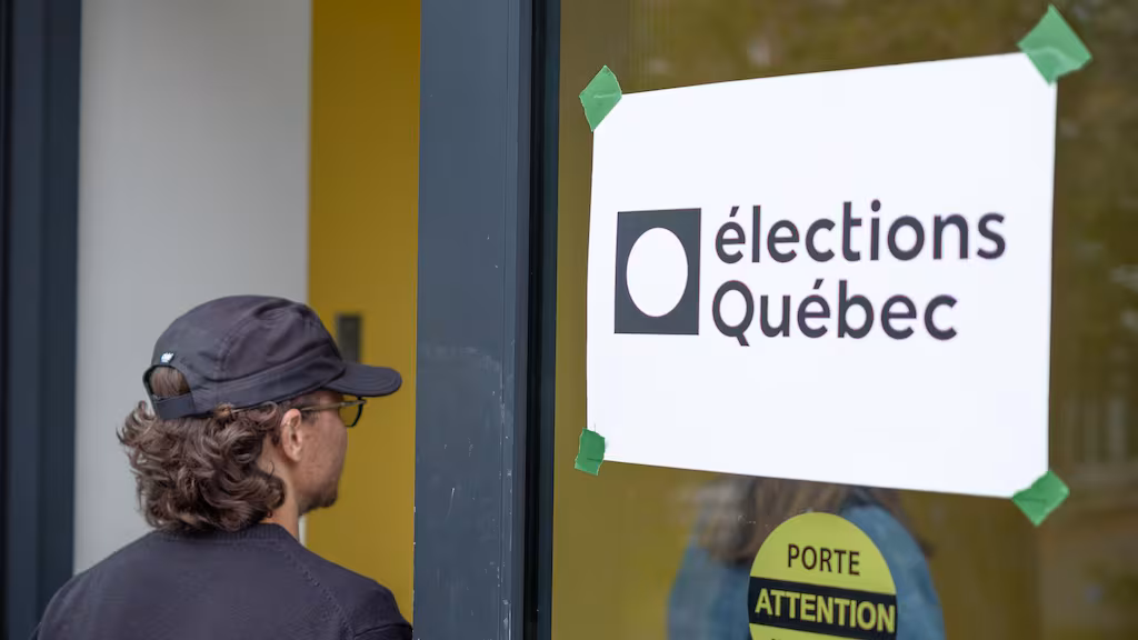 Un homme portant une casquette regarde une affiche d'Élections Québec collée sur une porte vitrée.