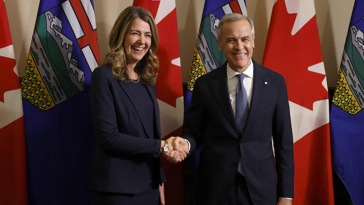 戴斯敏（Danielle Smith）和卡尼在艾伯塔省和加拿大国旗前微笑握手。