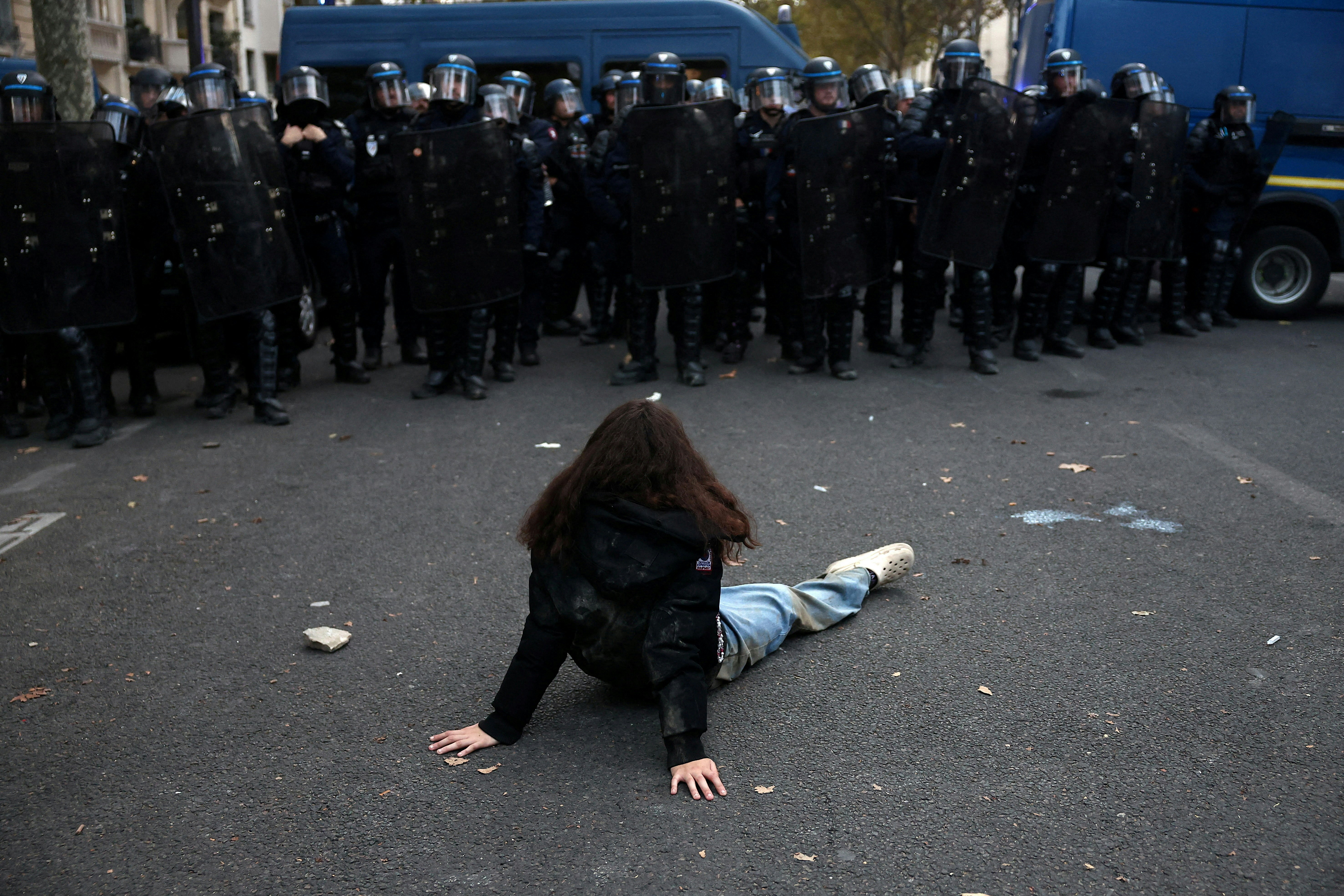 2026年10月13日，法国巴黎，一名示威者坐在地上，面对法国防暴警察。（Reuters）