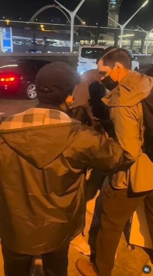 一名在现场自报姓名为「Jing Zhao」的华人女子，在机场航站楼外被多名便衣人员控制并带上一辆白色厢型车。面对旁人的追问，现场人员确认自己属于美国移民与海关执法局（ICE），并称带走女子的原因是「违反移民规定」。（IG@veganchefchristucker影片截图）
