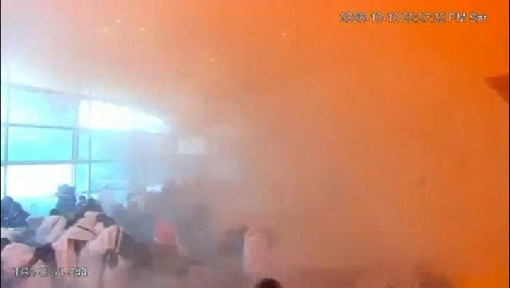 在这张来自发布影片的截图中，闭路电视片段显示了2026年10月10日沙特阿拉伯利雅得哈立德国王国际机场遇袭瞬间，民众在烟雾中的反应。（Reuters）