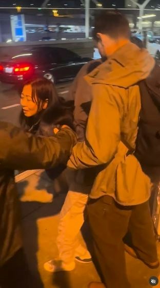 一名在现场自报姓名为「Jing Zhao」的华人女子，在机场航站楼外被多名便衣人员控制并带上一辆白色厢型车。面对旁人的追问，现场人员确认自己属于美国移民与海关执法局（ICE），并称带走女子的原因是「违反移民规定」。（IG@veganchefchristucker影片截图）