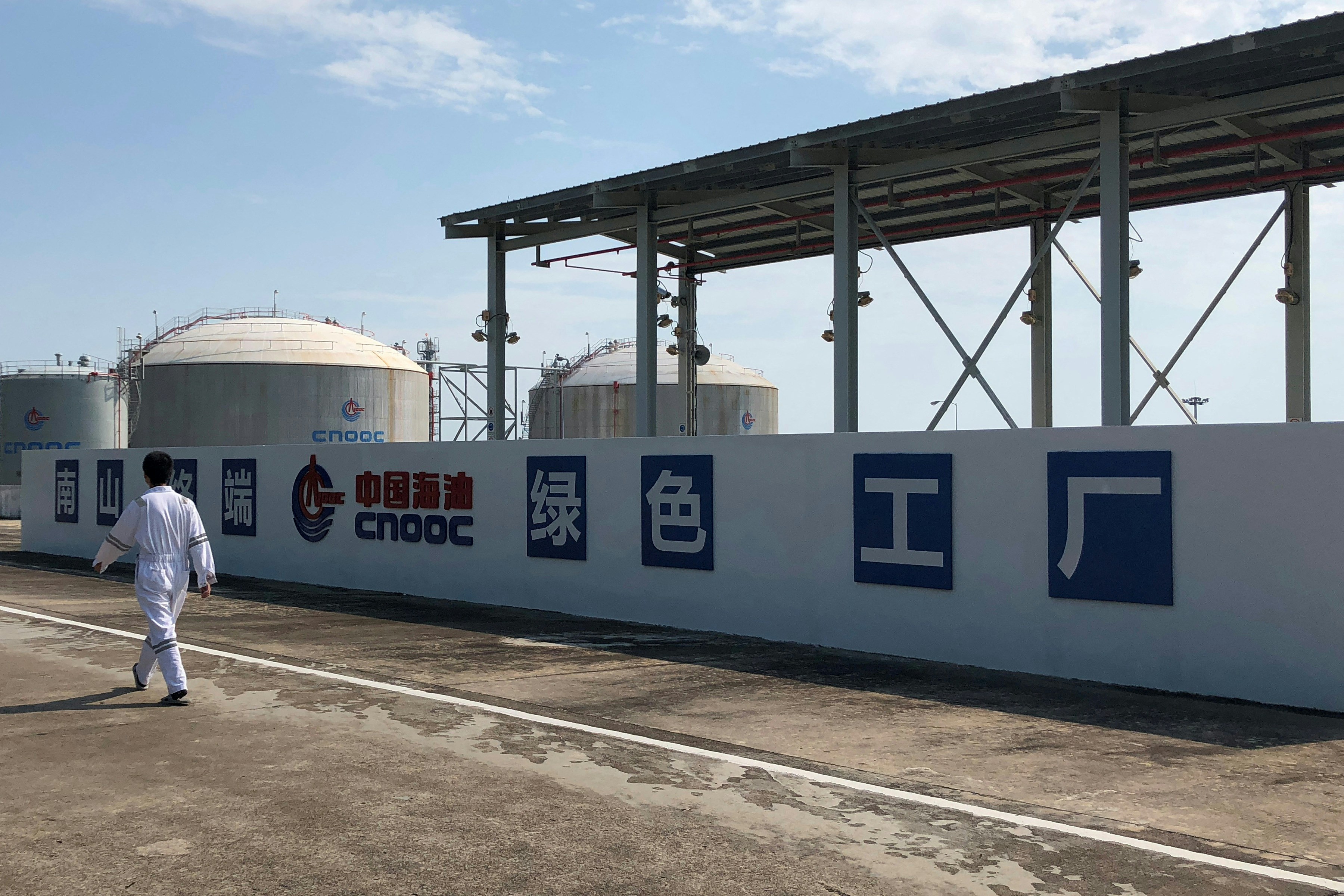 2019年9月24日,中国海南省,一名工人走过南山液化天然气 (LNG) 终端的中国海洋石油总公司 (CNOOC) 标志。(Reuters)
